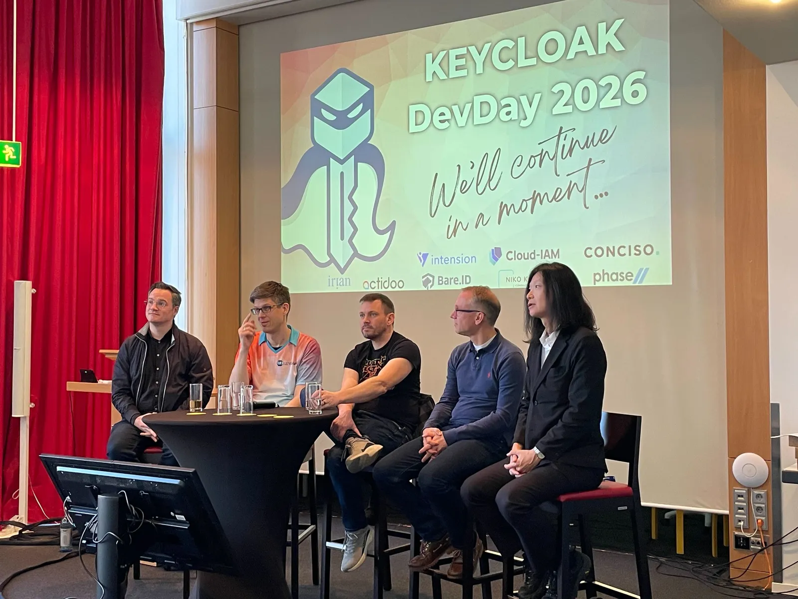 A panel of speakers on stage at Keycloak DevDay 2026, under the sponsors slide